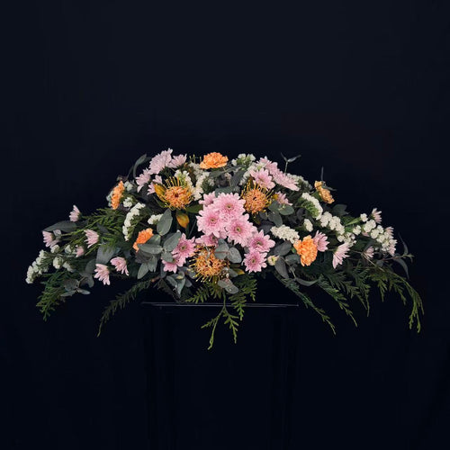 Casket spray with seasonal flowers and natural foliage