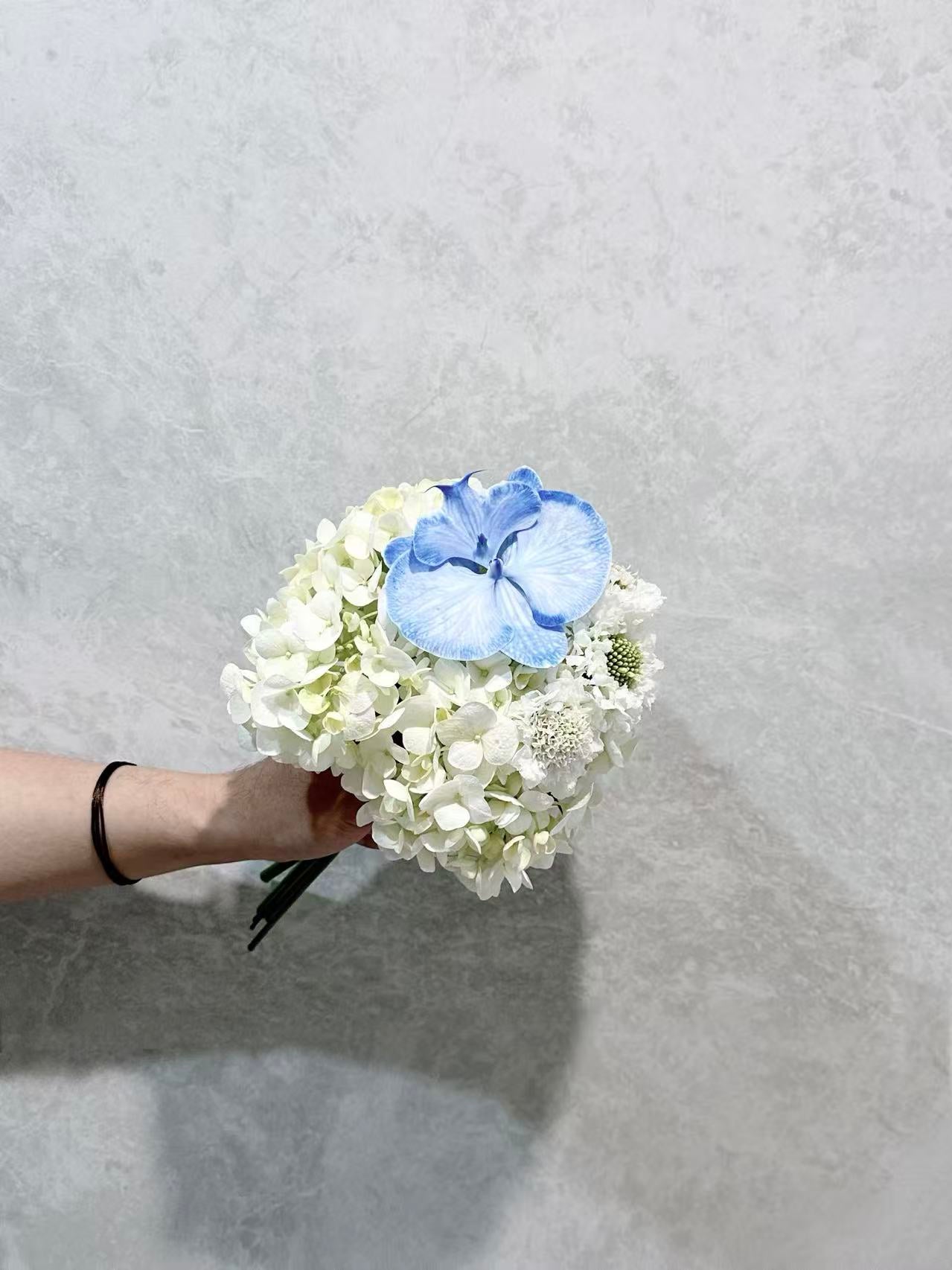 Round white flower bouquet with blue accent