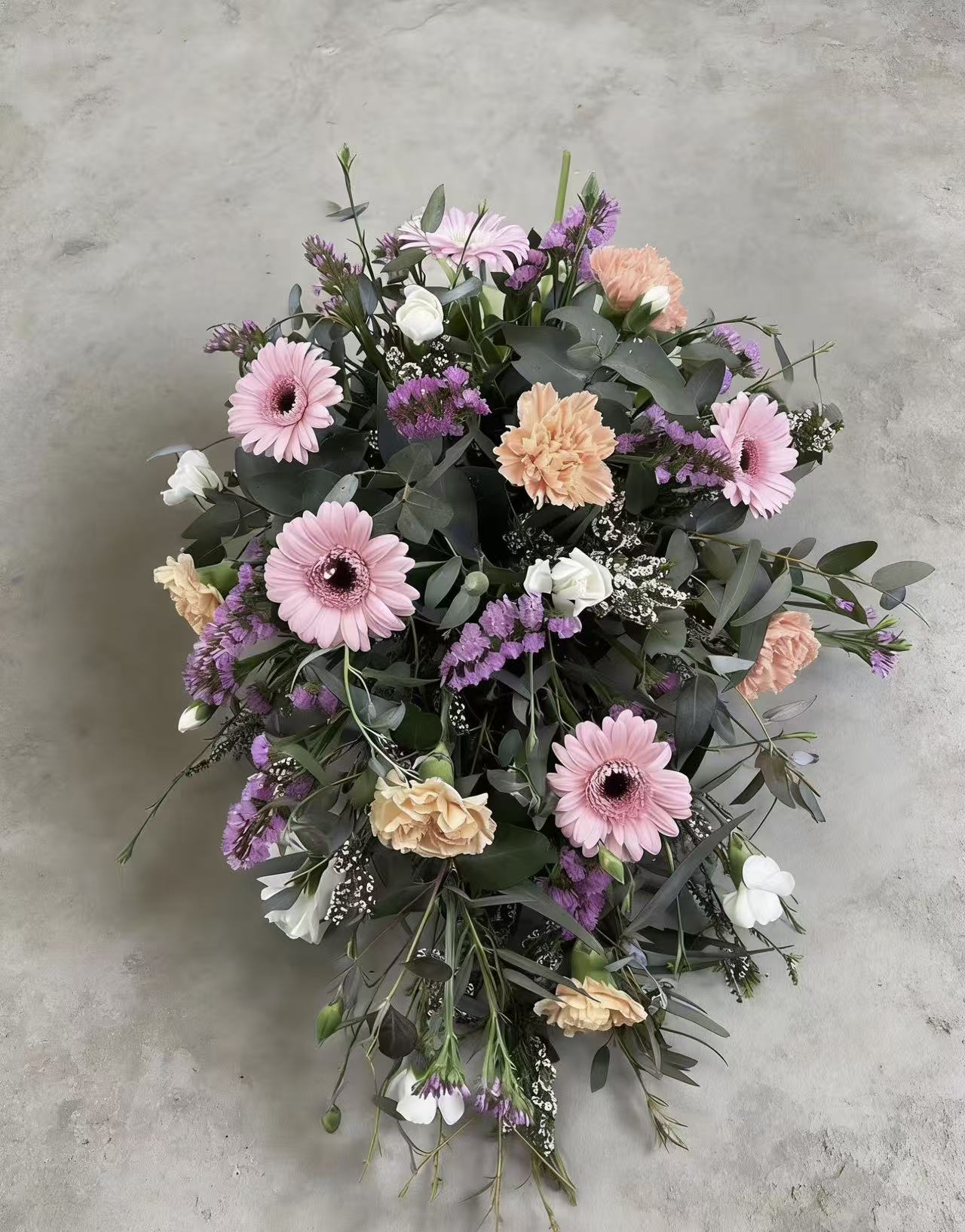 Teardrop-shaped funeral flower tribute in pink, orange, purple and white